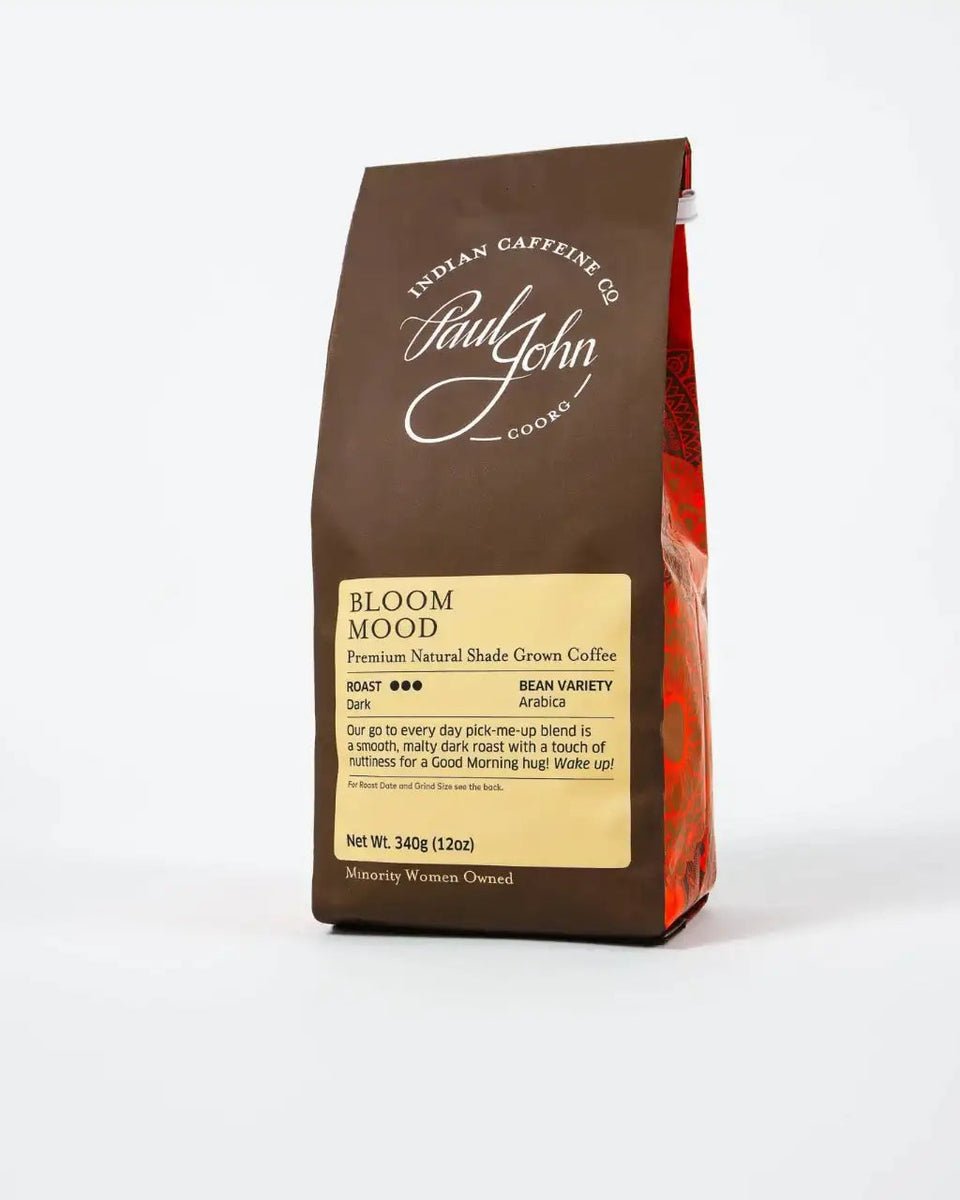 A bag of Paul John Coffee's Bloom Mood coffee, featuring a dark brown package with a cream-colored label and a red patterned side panel, set against a plain white background.